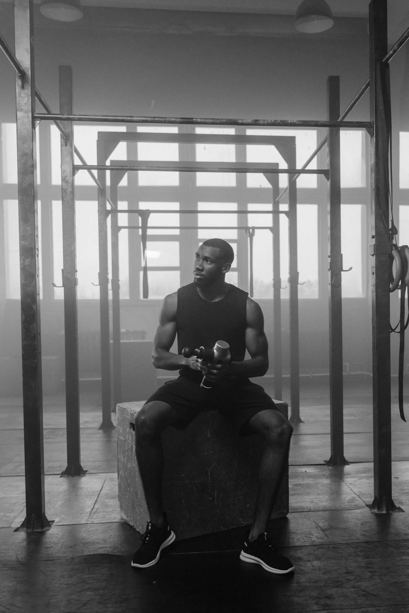 A man exercising with dumbbells in a gym, captured in monochrome.